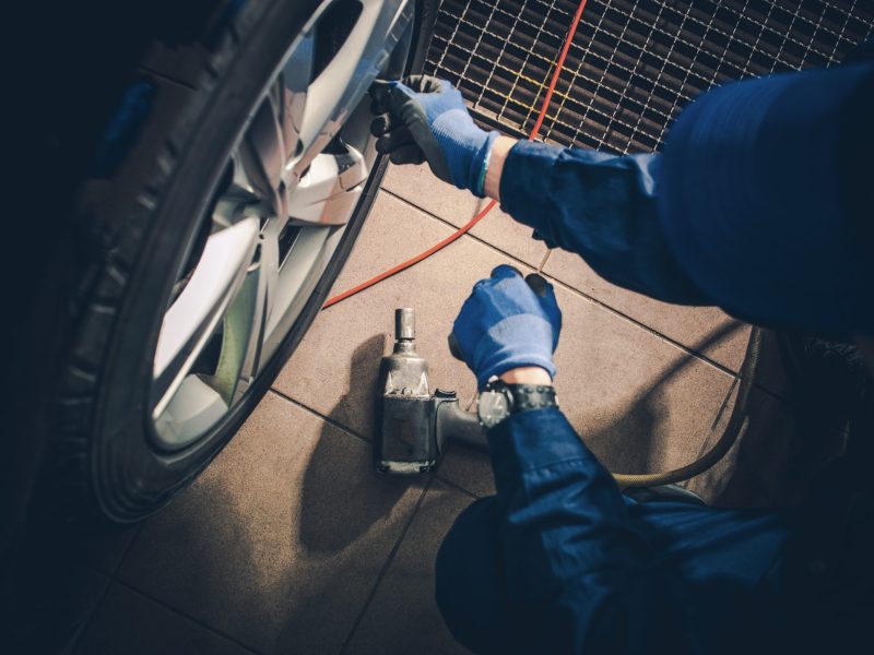 Seasonal Tire Replacement. Car Service Worker Replacing Vehicle Tires and Rotate the Wheels.